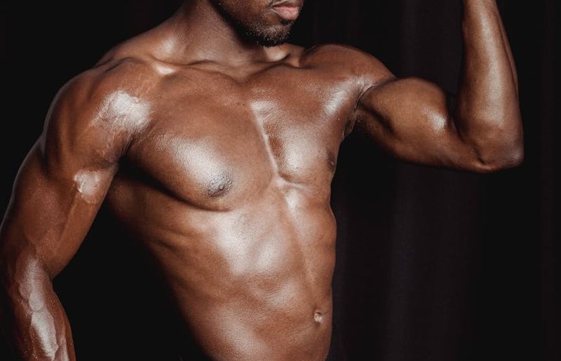 Man holding a difficult bodyweight pose, showing muscle definition.